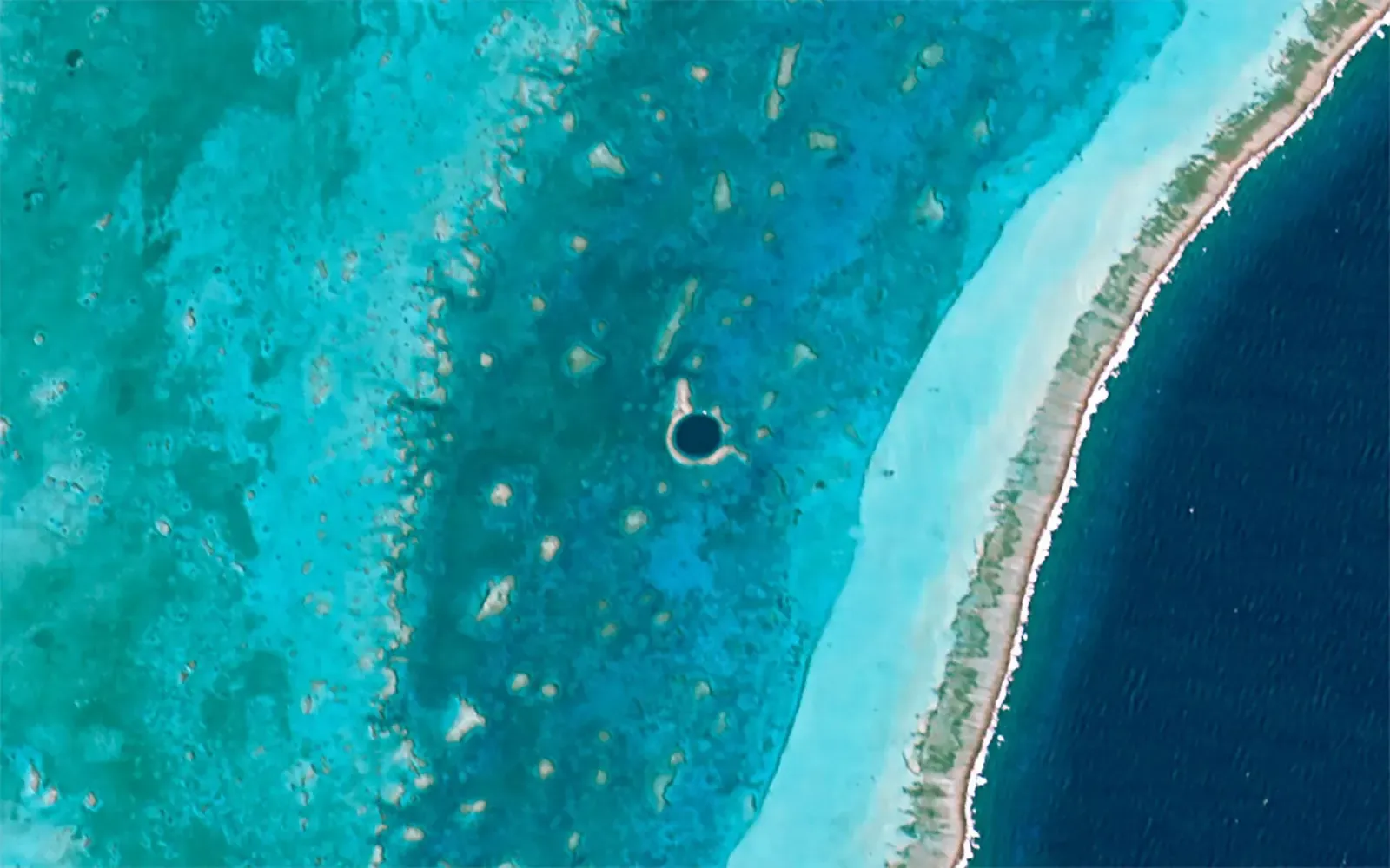 Satellite view of the Great Blue Hole, a circular deep-blue sinkhole ringed by shallow turquoise reef within Lighthouse Reef, Belize