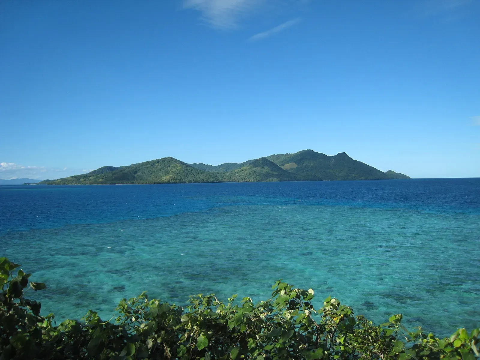 Turquoise reef flats stretch toward Beqa Island's forested peaks under a clear sky
