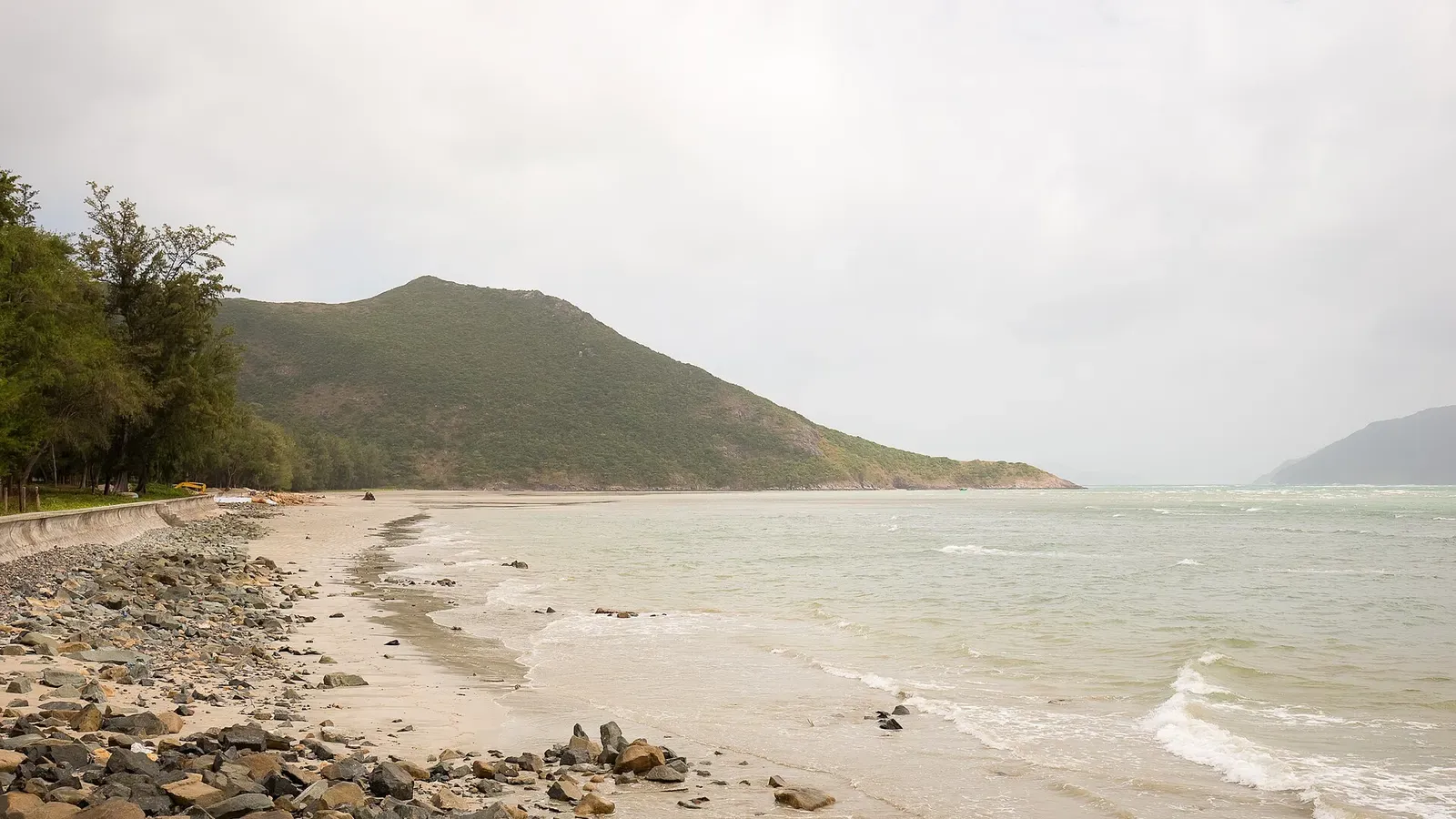 Rocky shoreline and forested hills along Con Son Island's coast in the Con Dao archipelago, Vietnam.