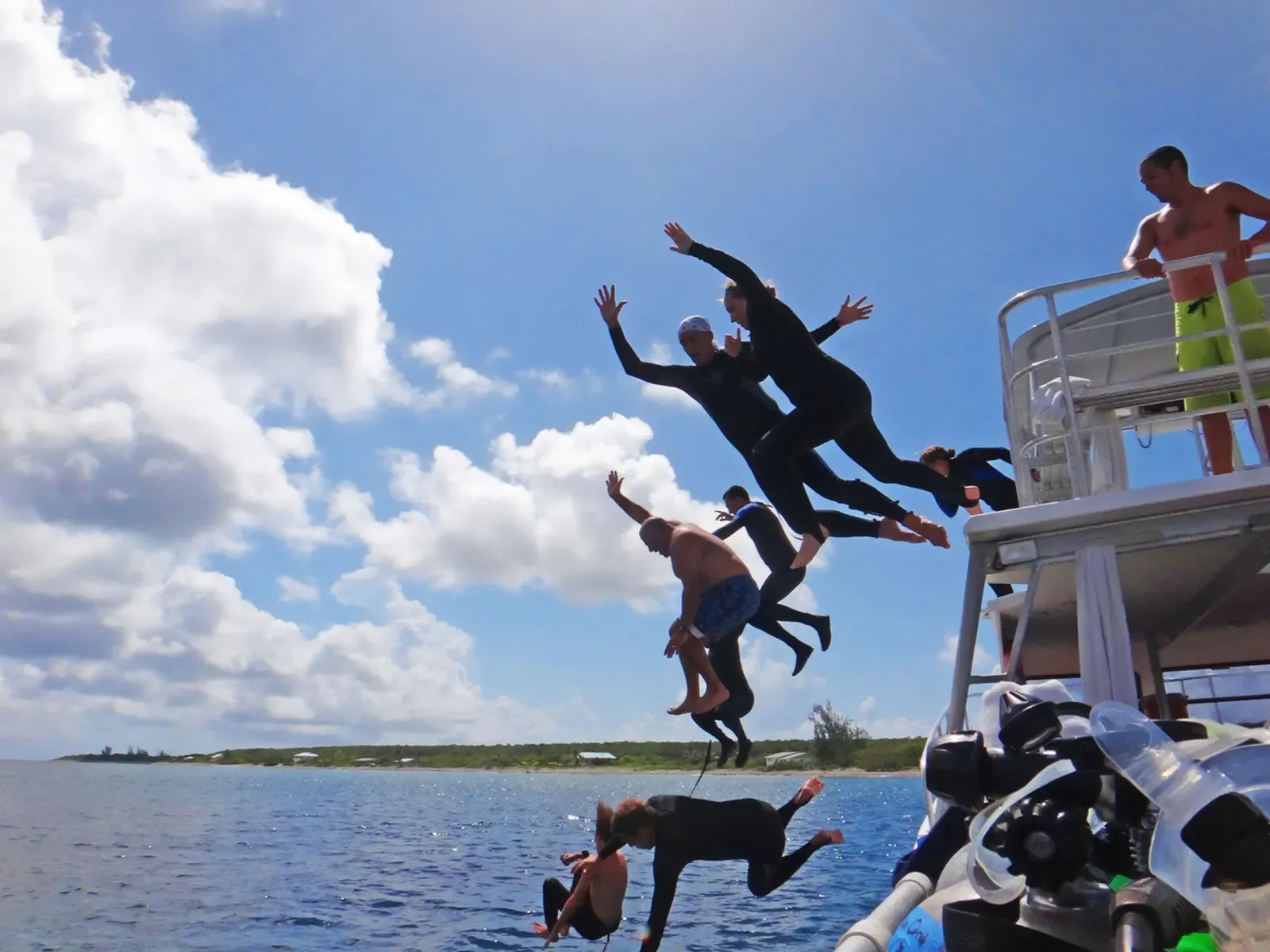 Divers leaping off the dive boat into the water off Cayman Brac's Plymouth Rock site