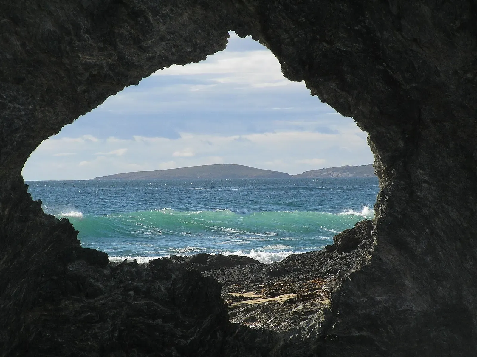 Montague Island seen across the water through the natural rock arch at Narooma