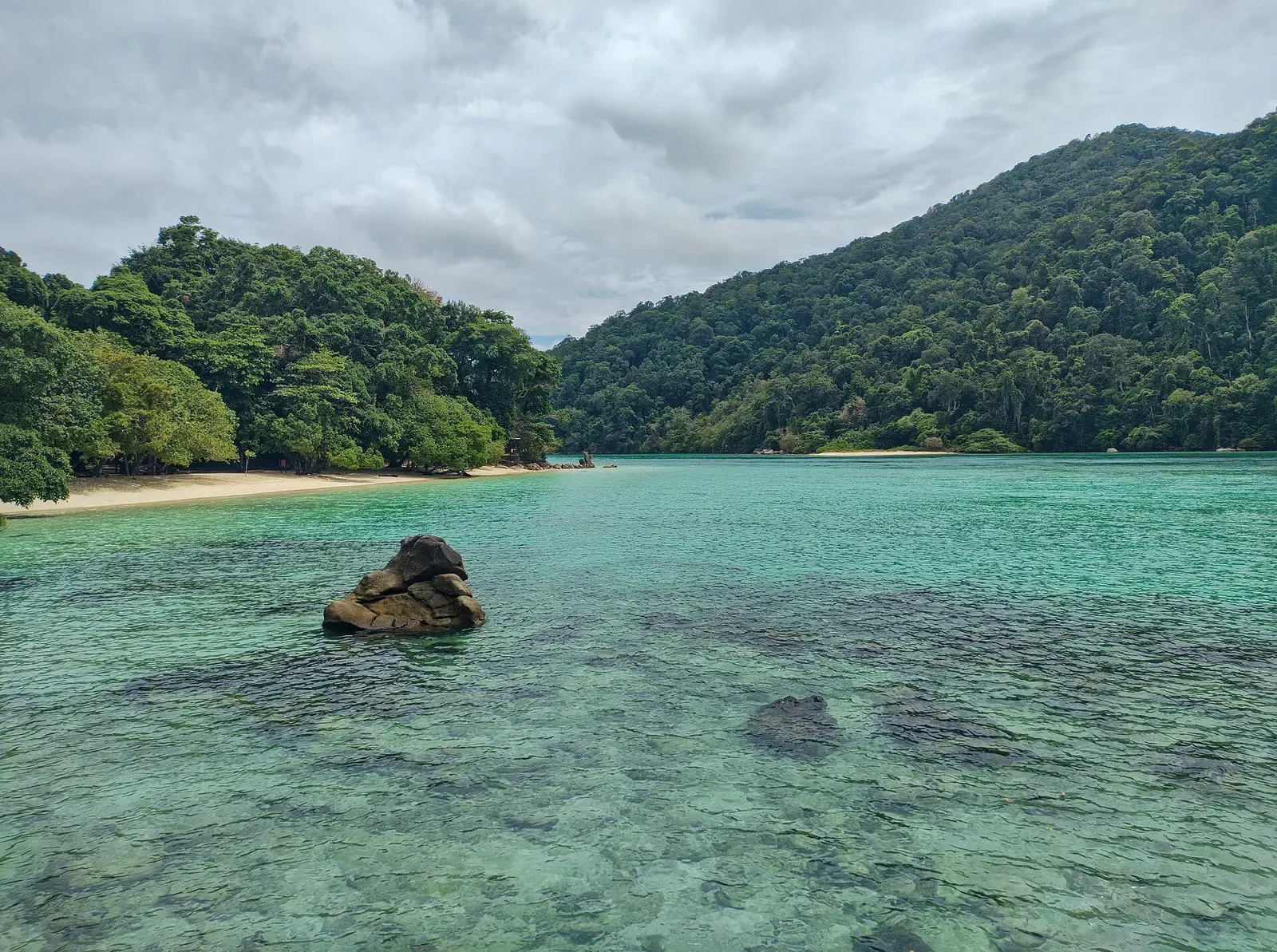 A weathered granite boulder sits in clear turquoise shallows in Chong Khad Bay, Surin Islands