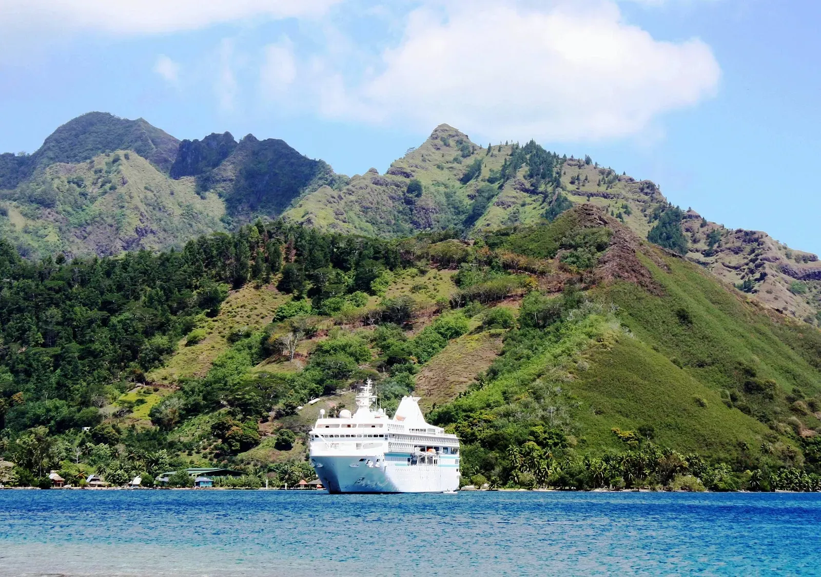 A ship anchored in Cook Bay's turquoise lagoon beneath Moorea's steep green ridgeline