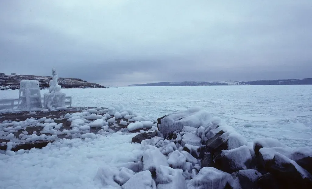Chunks of drift ice line the shore of Conception Bay with Bell Island visible across the water