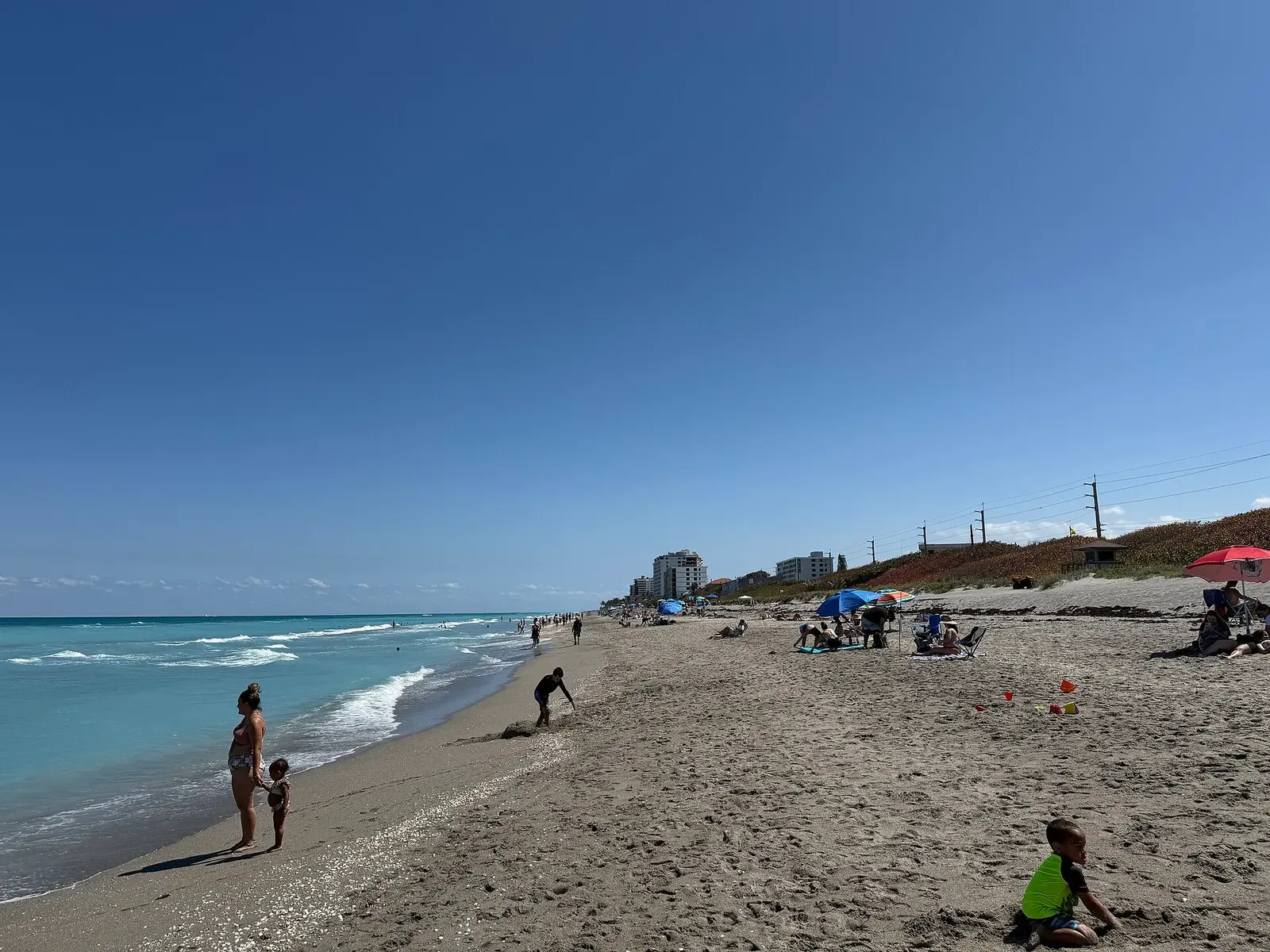 Sweeping coastal view of Juno Beach with gentle waves rolling onto pale Florida sand