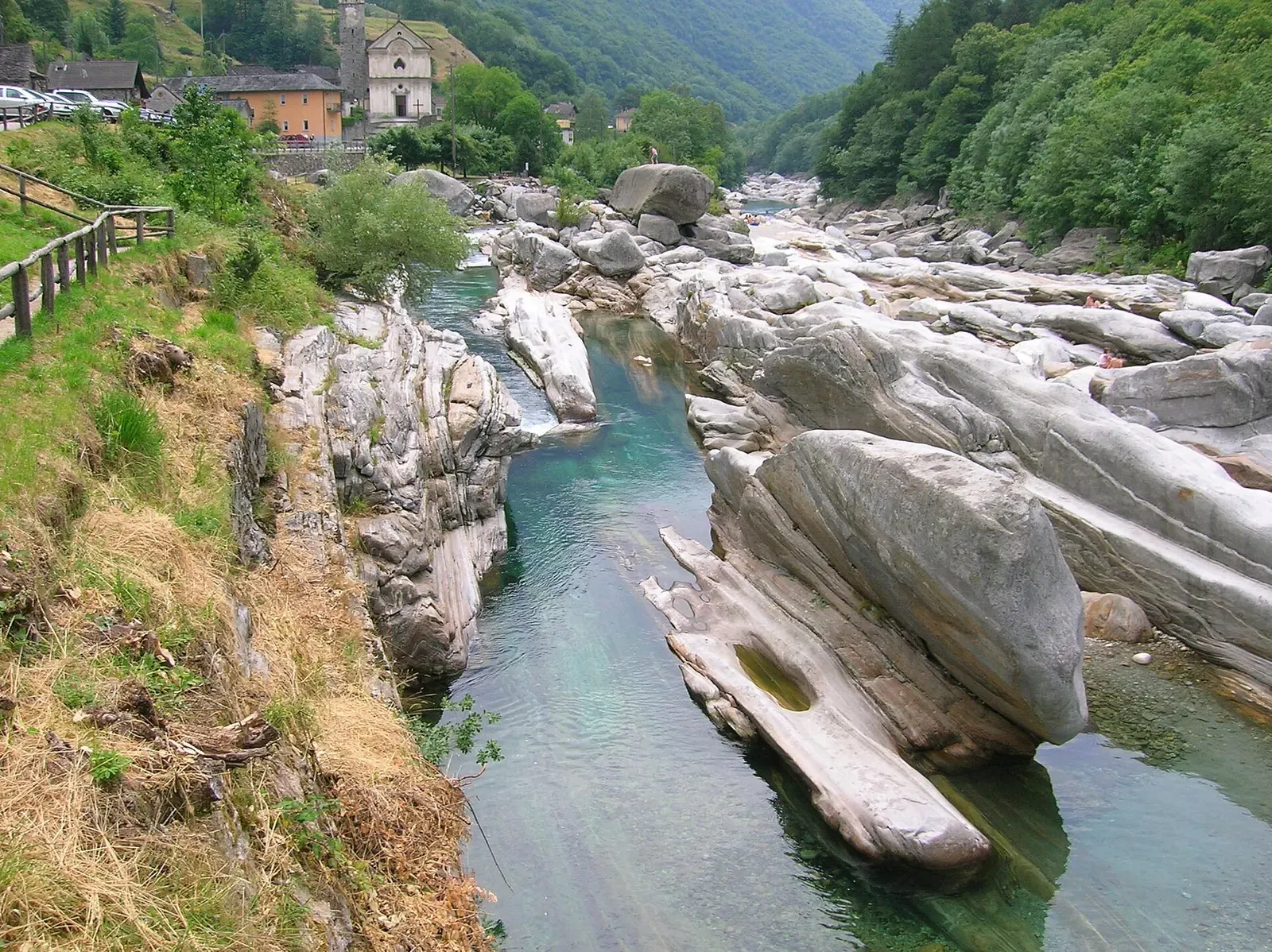 Clear turquoise channel of the Verzasca river winding between smooth granite boulders at Lavertezzo