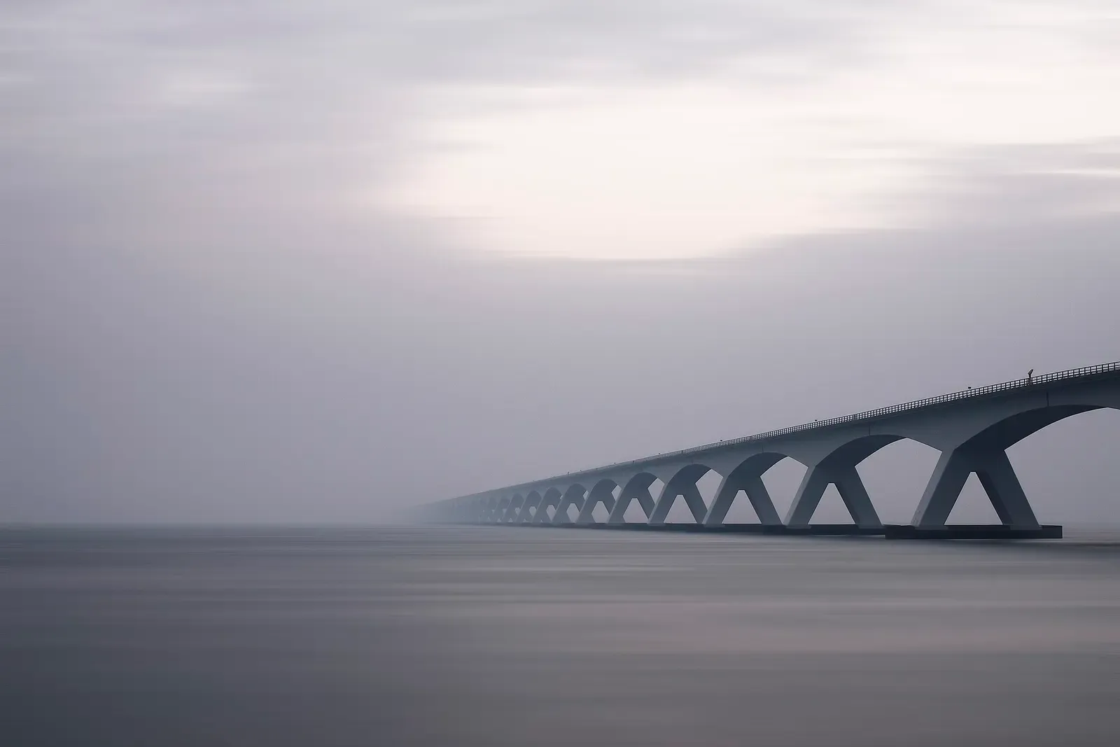 The Zeeland Bridge fading into fog over the still water of the Oosterschelde