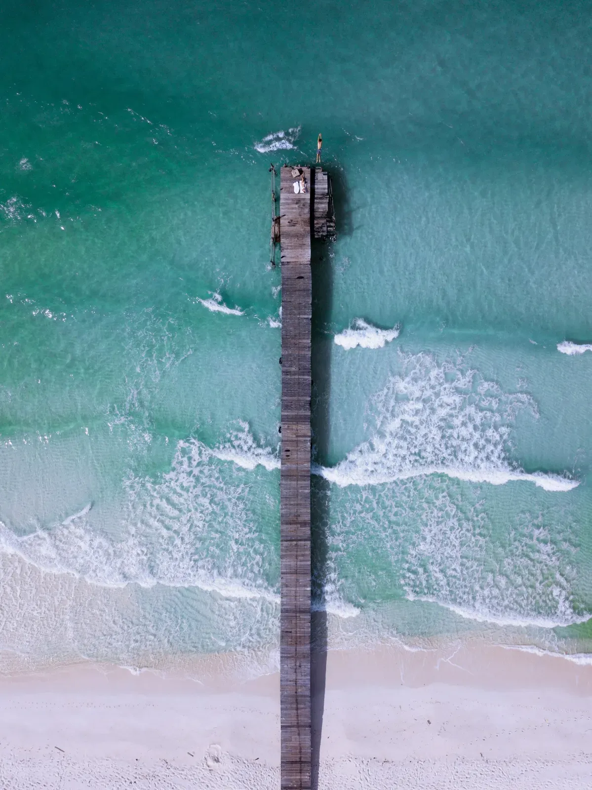 Aerial view of a wooden pier reaching into turquoise water off Koh Rong Island