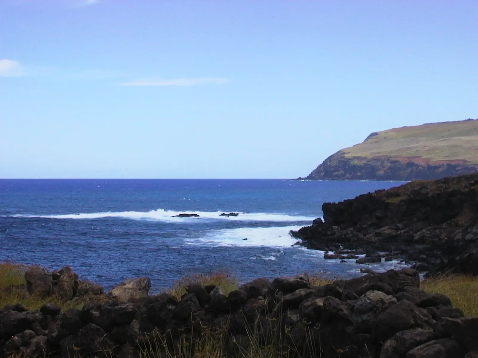 A quiet bay along the coast of Rapa Nui with clear blue water and a rocky headland