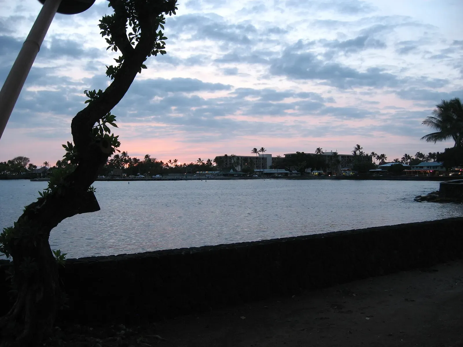 Sunset over Kailua-Kona's waterfront, with town lights beginning to glow along the shore