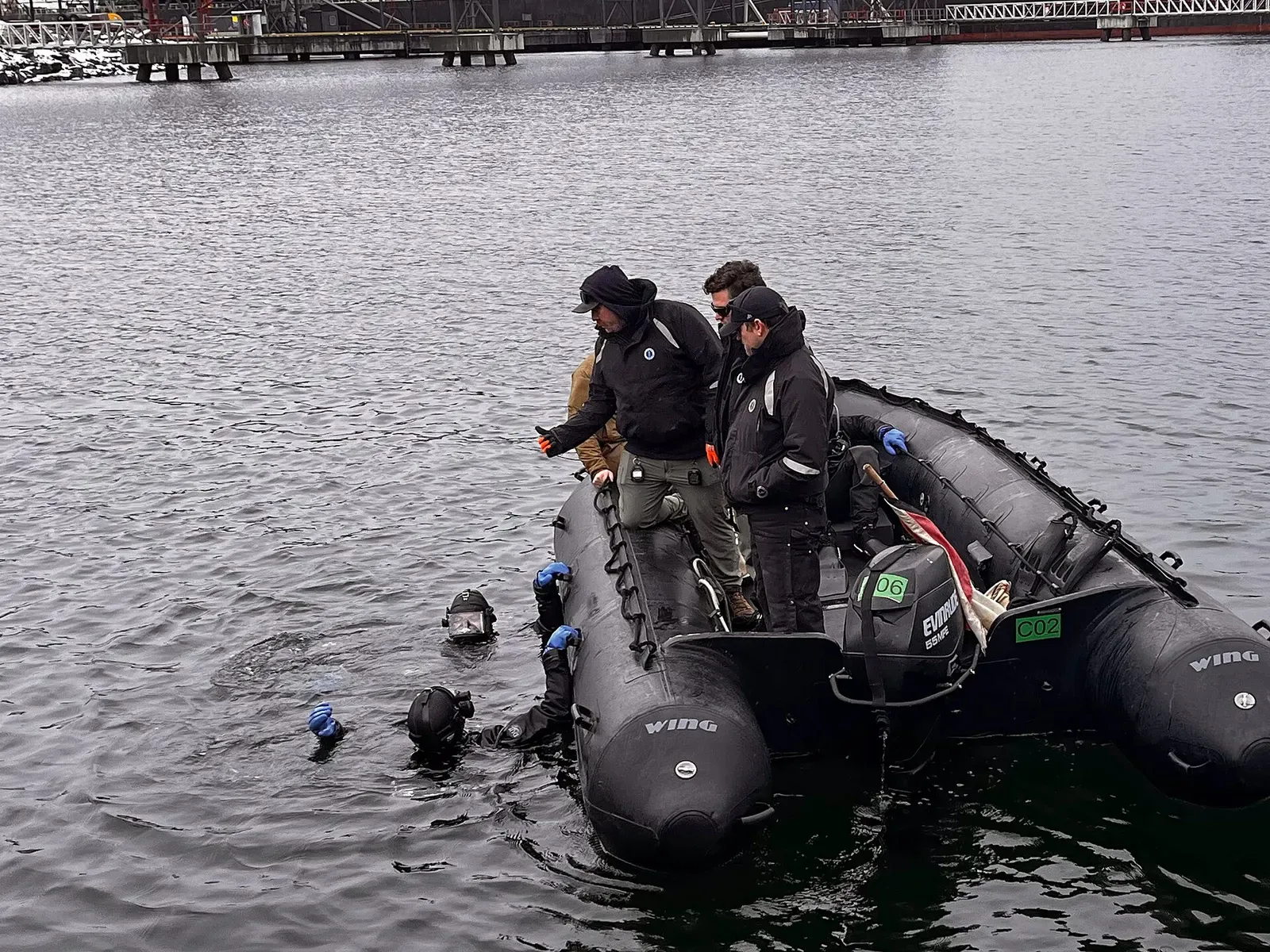 Divers gear up beside an inflatable boat before descending into Narvik's harbour waters