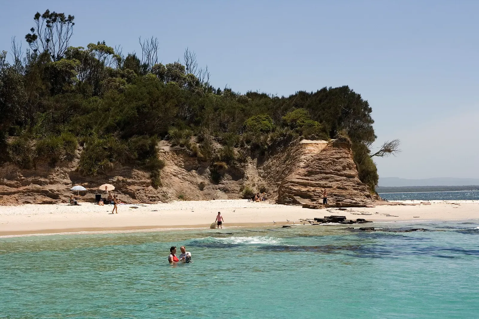 Layered sandstone cliffs rising above a sheltered beach on Jervis Bay