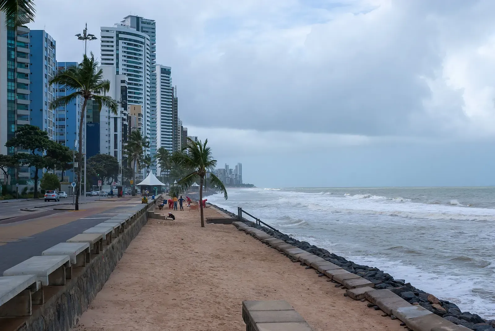 Swimmers wading in a shallow natural pool formed by the reef at Boa Viagem beach in Recife