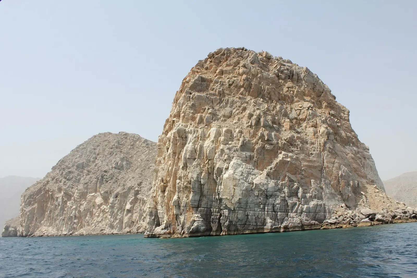 A weathered limestone pinnacle rises from the sea off the Musandam peninsula