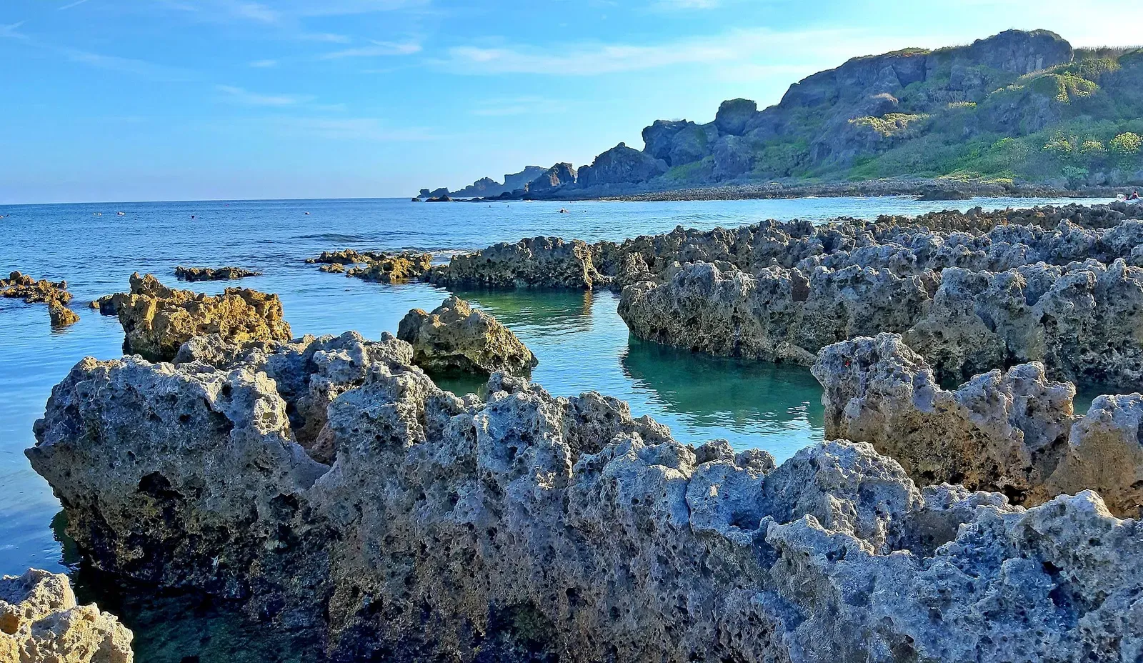 Jagged coral-rock shoreline at Little Bali Island with the Hengchun headland beyond.
