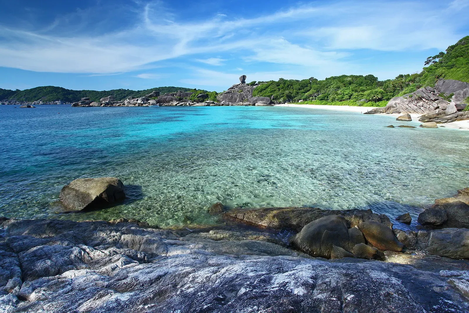 Smooth granite boulders rise from a shallow reef along a Similan Islands shoreline
