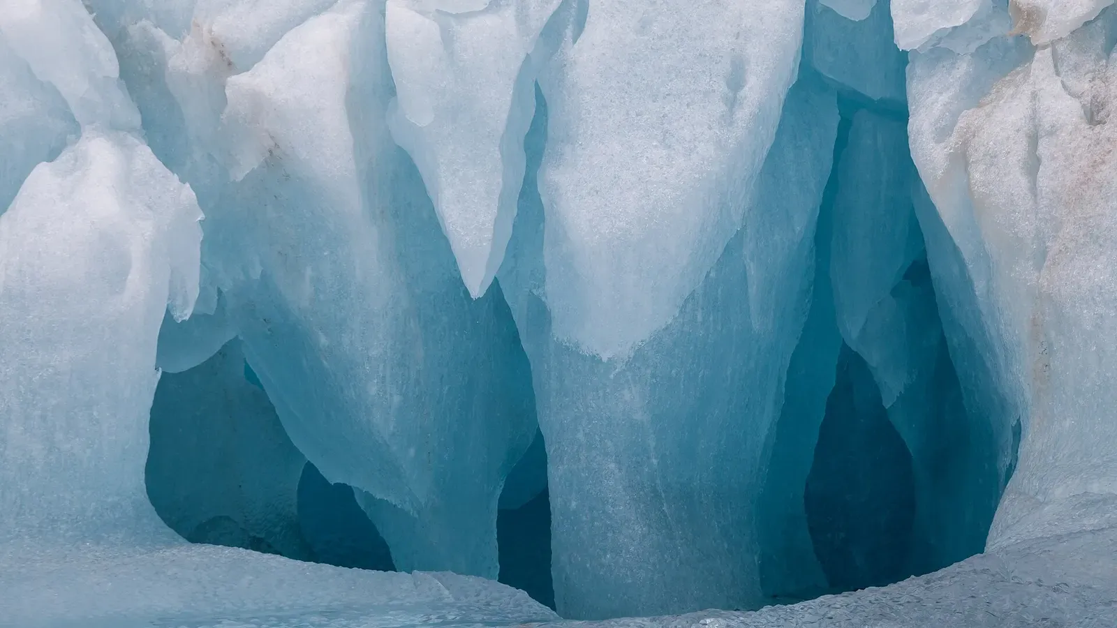 Weathered blue ice pillars and hollows on an iceberg face in Liefdefjord