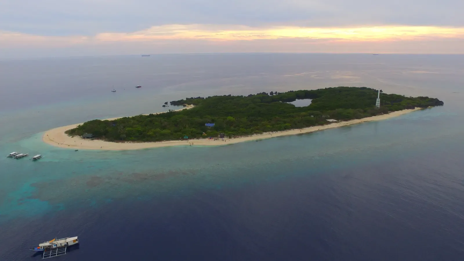 Aerial view of Apo Island's lighthouse islet ringed by reef and lagoon.