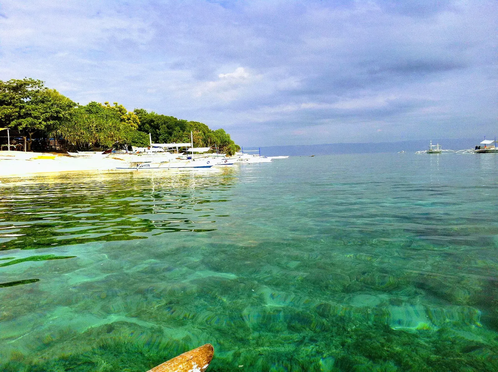 Dive boats moored over shallow reef water at Balicasag Marine Sanctuary