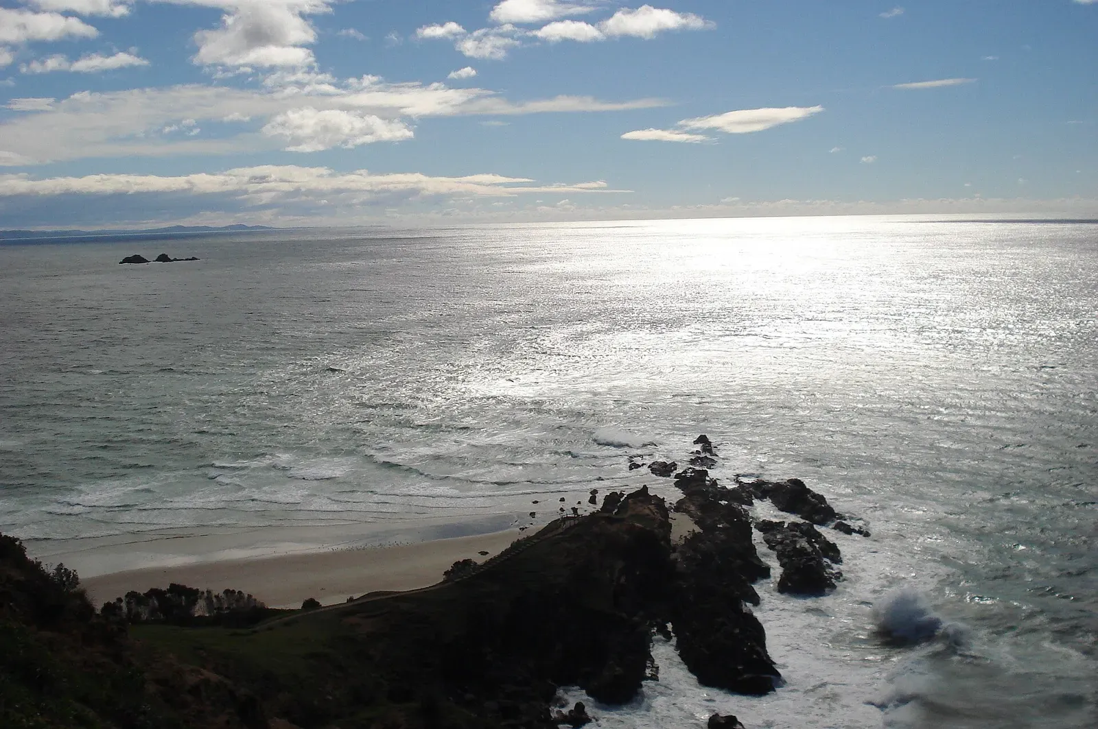 Sunlit ocean and rocky point at Byron Bay, gateway to the Julian Rocks dive site