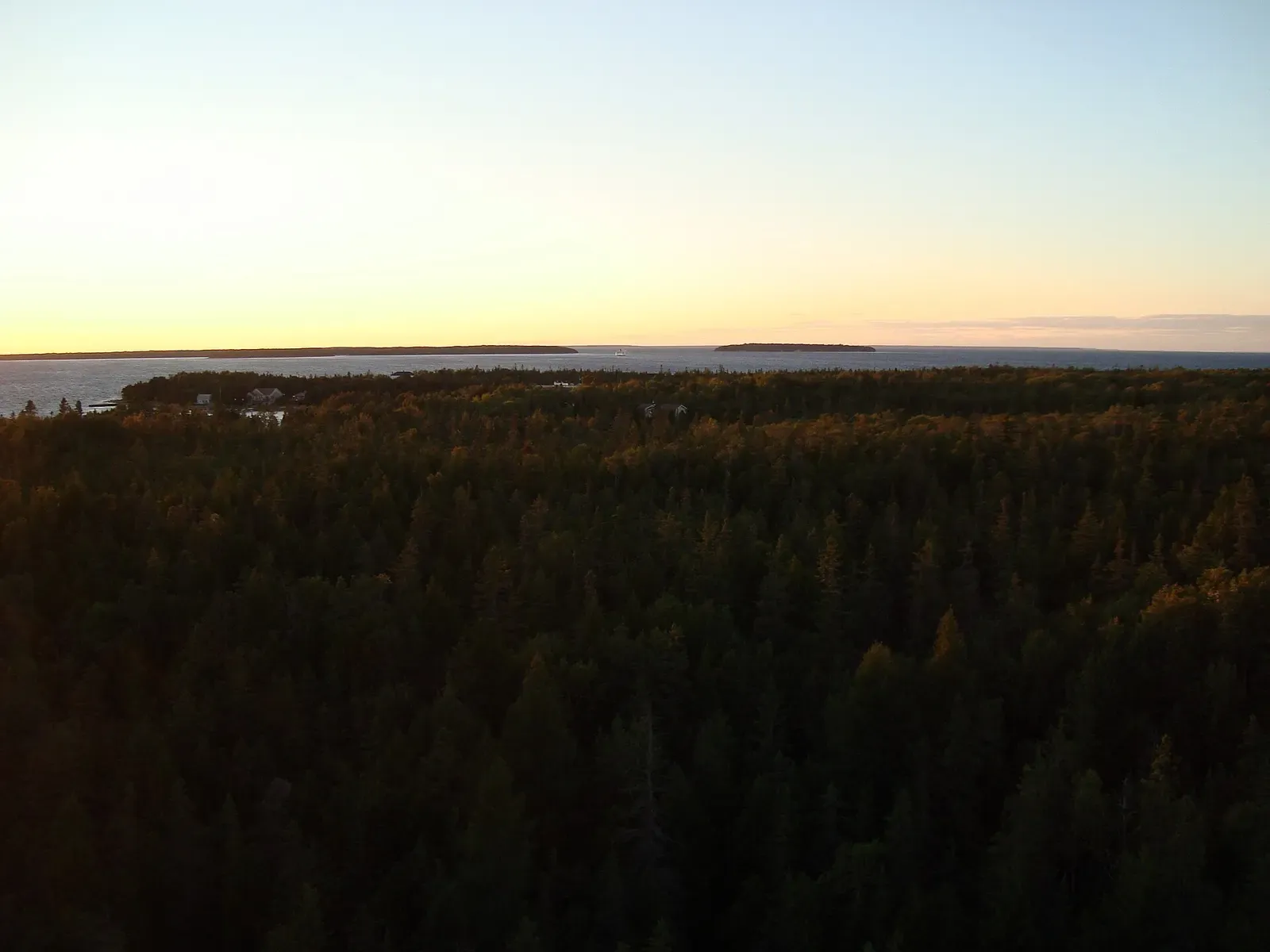 Forested shoreline and distant islands at sunset near Fathom Five National Marine Park