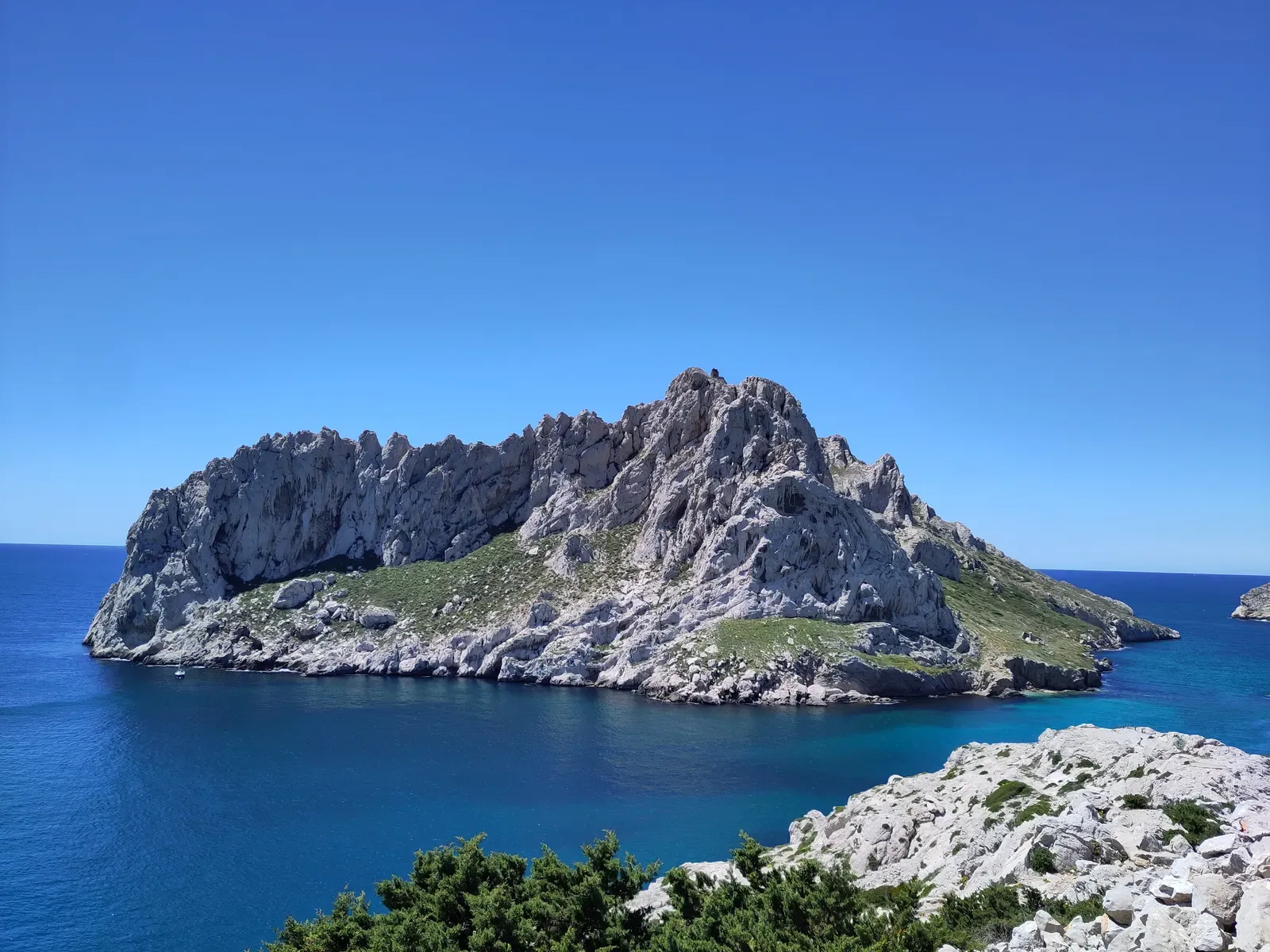 Rugged white limestone ridge of Île Maïre rising from deep blue sea under a clear sky