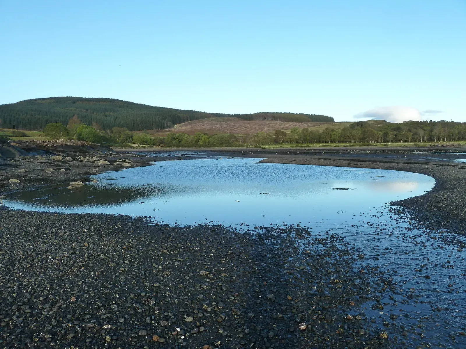 Tidal pool reflecting the sky on a pebble beach at Savary Bay along the Sound of Mull