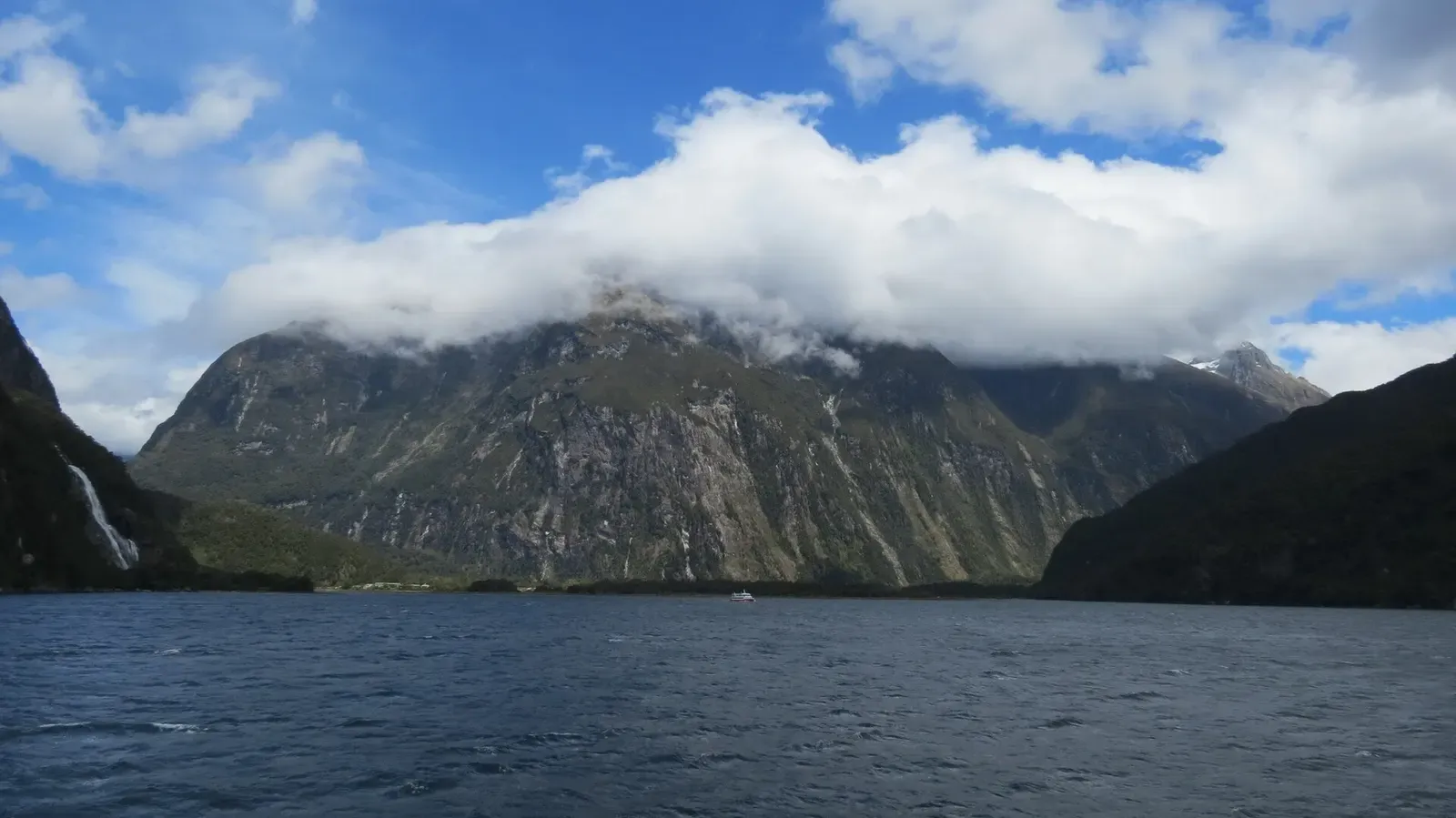 Cloud-wrapped peak reflected in the still waters of Milford Sound