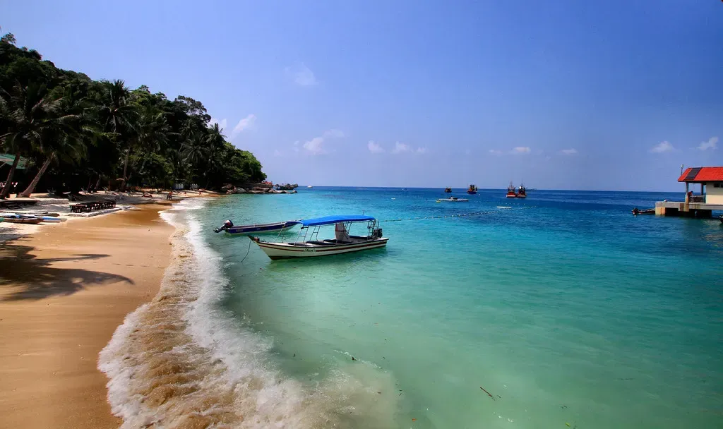 A traditional wooden boat rests on the shore of Perhentian Besar Island, Malaysia.