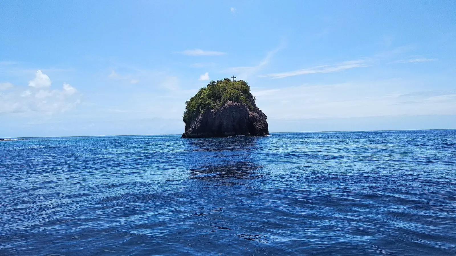 Small uninhabited rock islet rising from deep blue water off Mahengetang