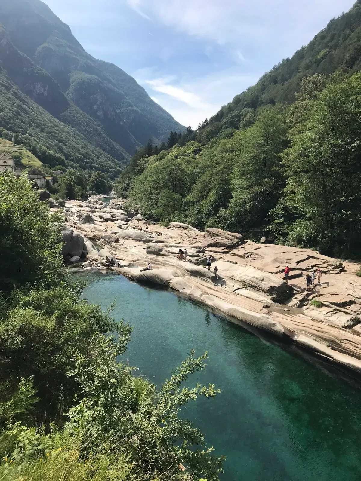 Aerial view of a deep emerald pool in the Verzasca river bordered by pale granite slabs