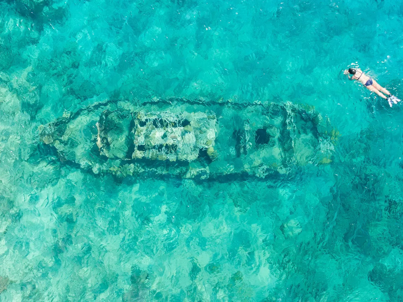 Aerial view of the small tugboat wreck resting in shallow turquoise water off Curaçao