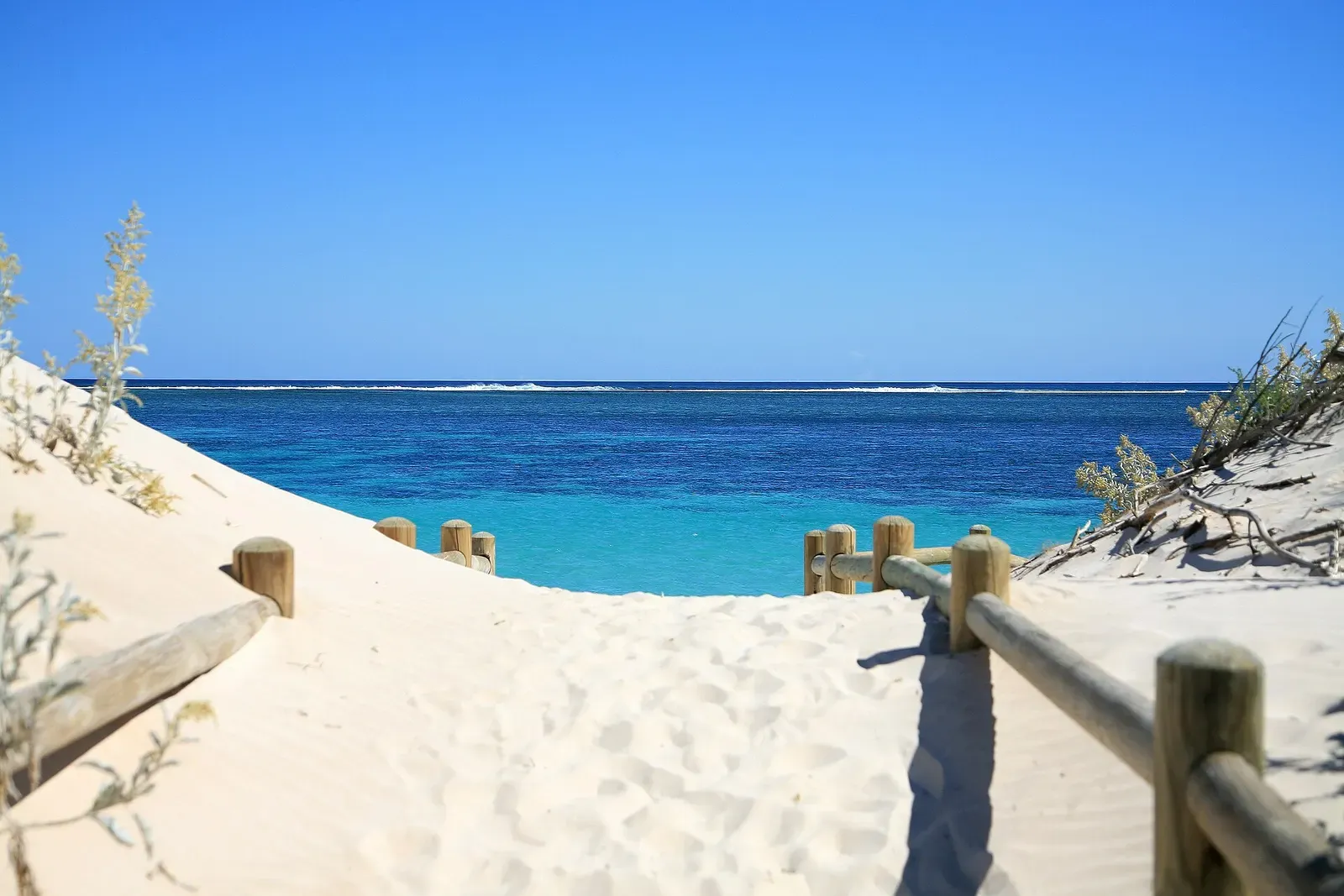 A sandy boardwalk leads to the turquoise shallows of Ningaloo Reef on Western Australia's coast.
