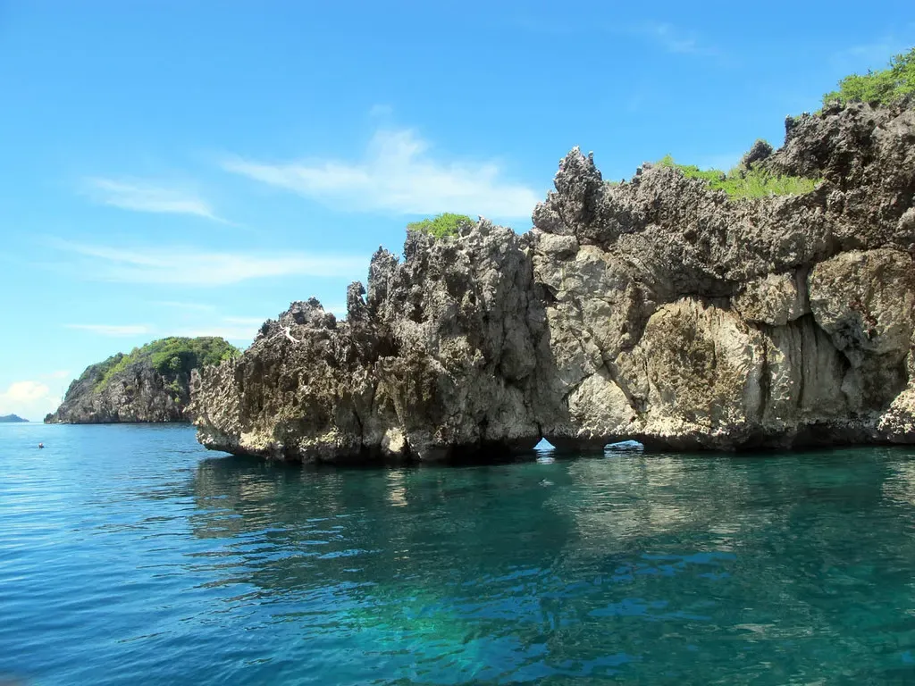 Jagged limestone karst islands rise from turquoise water along a Raja Ampat channel.