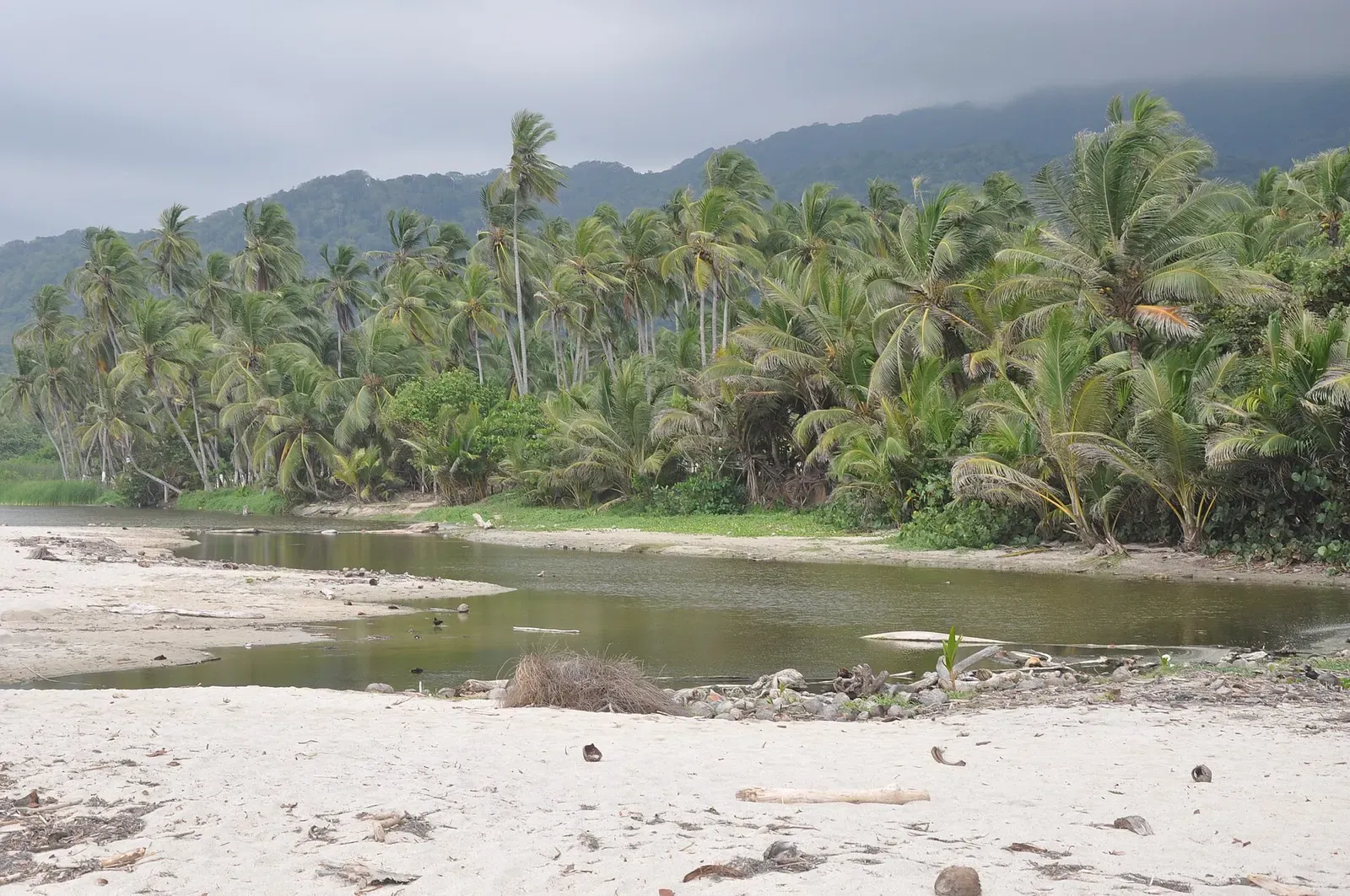 Boulder-strewn shoreline and a moored boat along the Tayrona park coast near Cabo San Juan