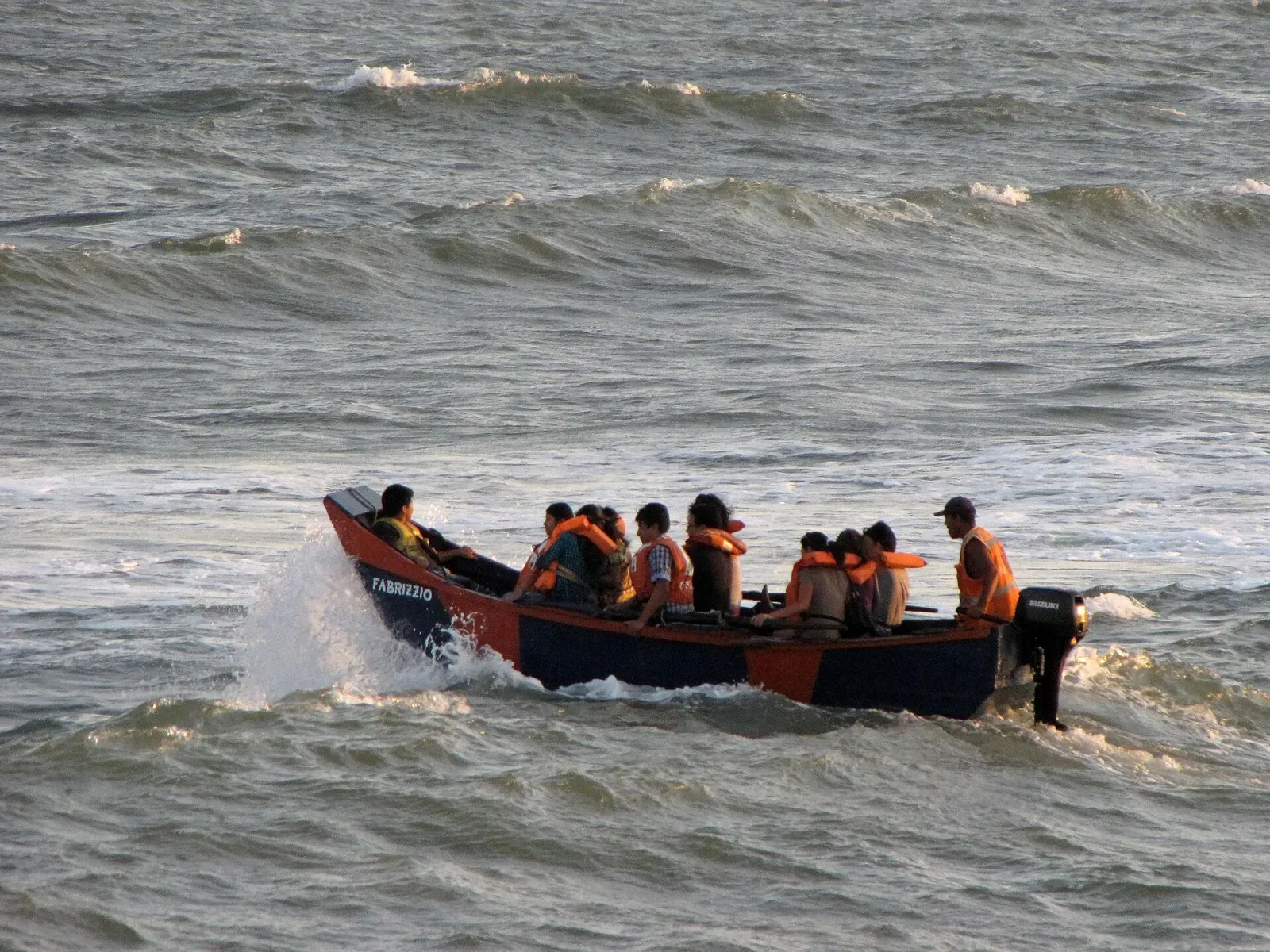 A small open boat loaded with passengers in life jackets crosses choppy seas toward the Palomino islands