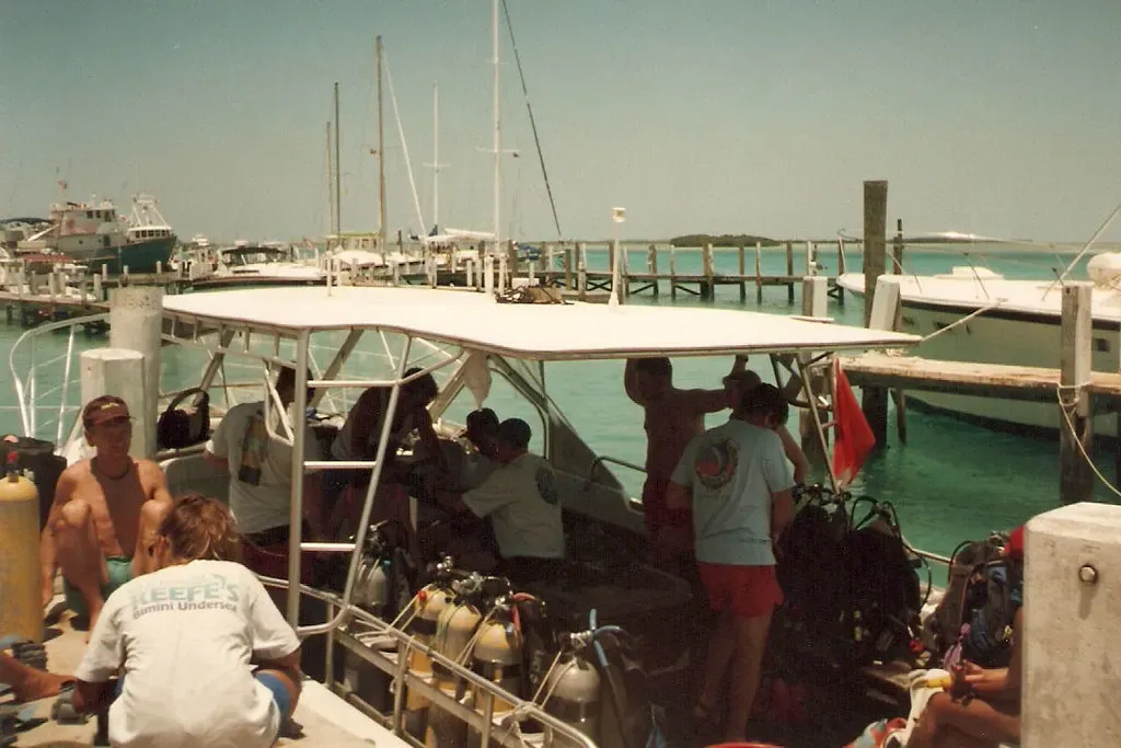 Divers load tanks and gear onto a dive boat tied up at a harbor dock.