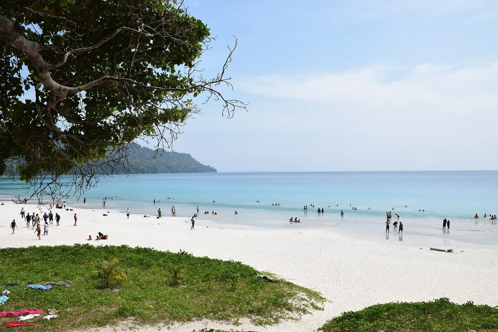 Visitors wading in calm turquoise water off a white sand beach on Havelock Island