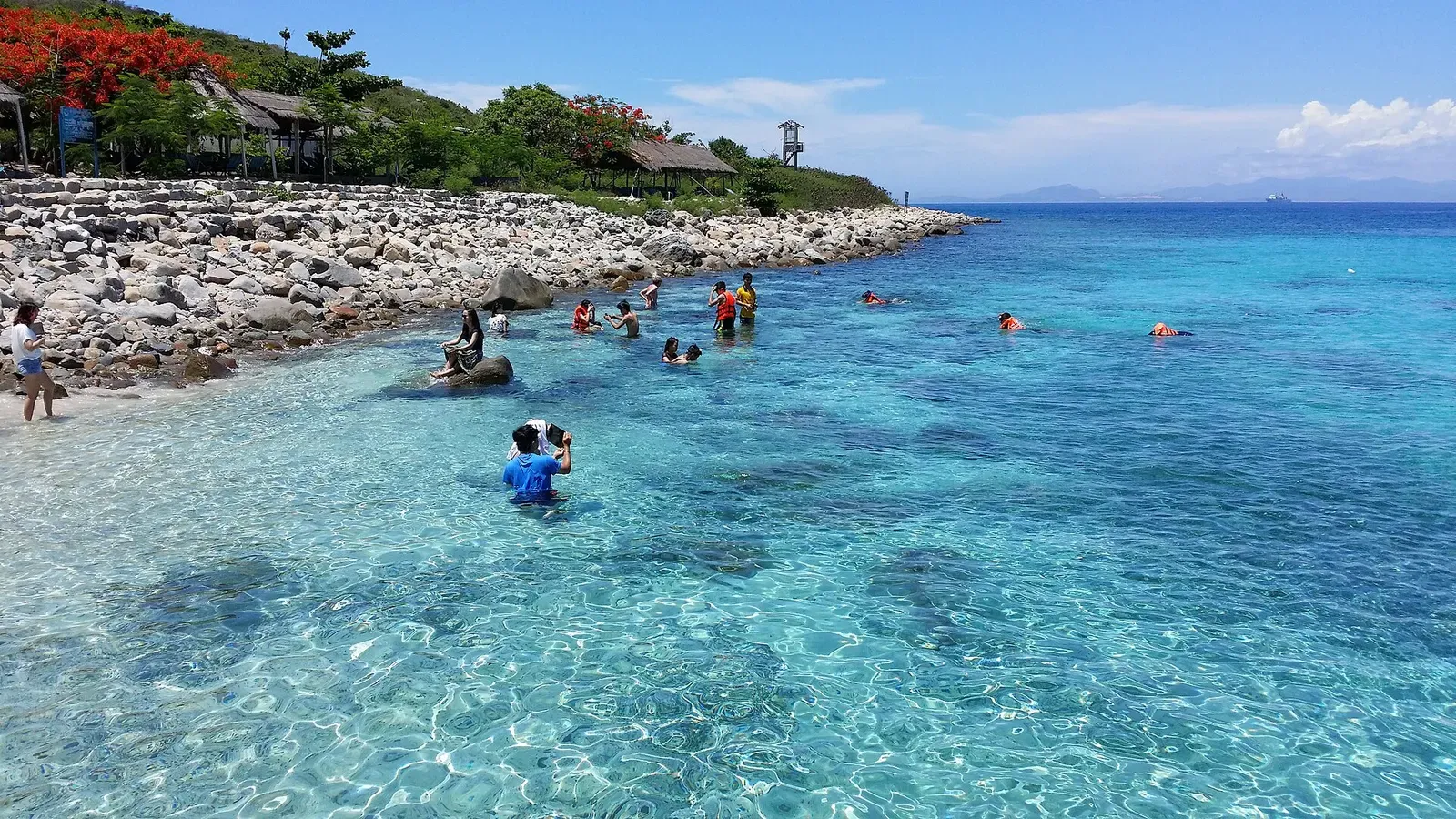 Snorkelers wade into clear turquoise water off Hon Mun Island near Nha Trang