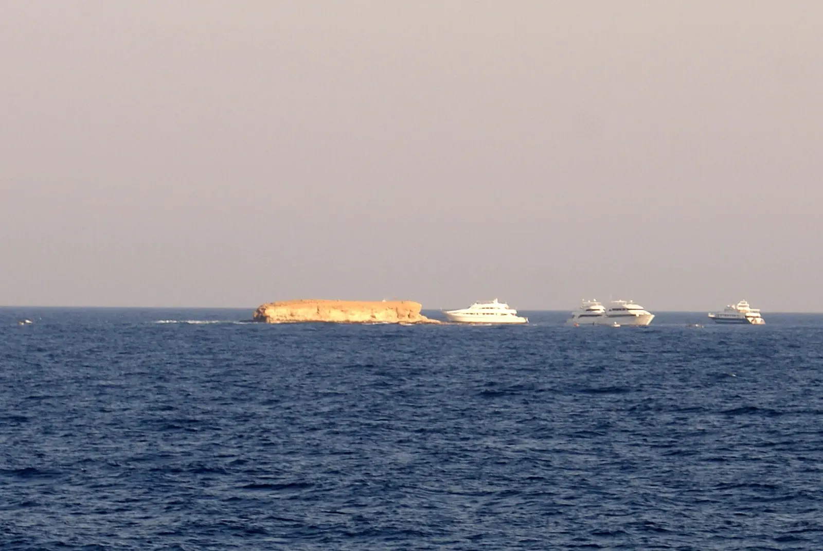 Little Brother Island viewed from the sea, with liveaboard boats anchored offshore