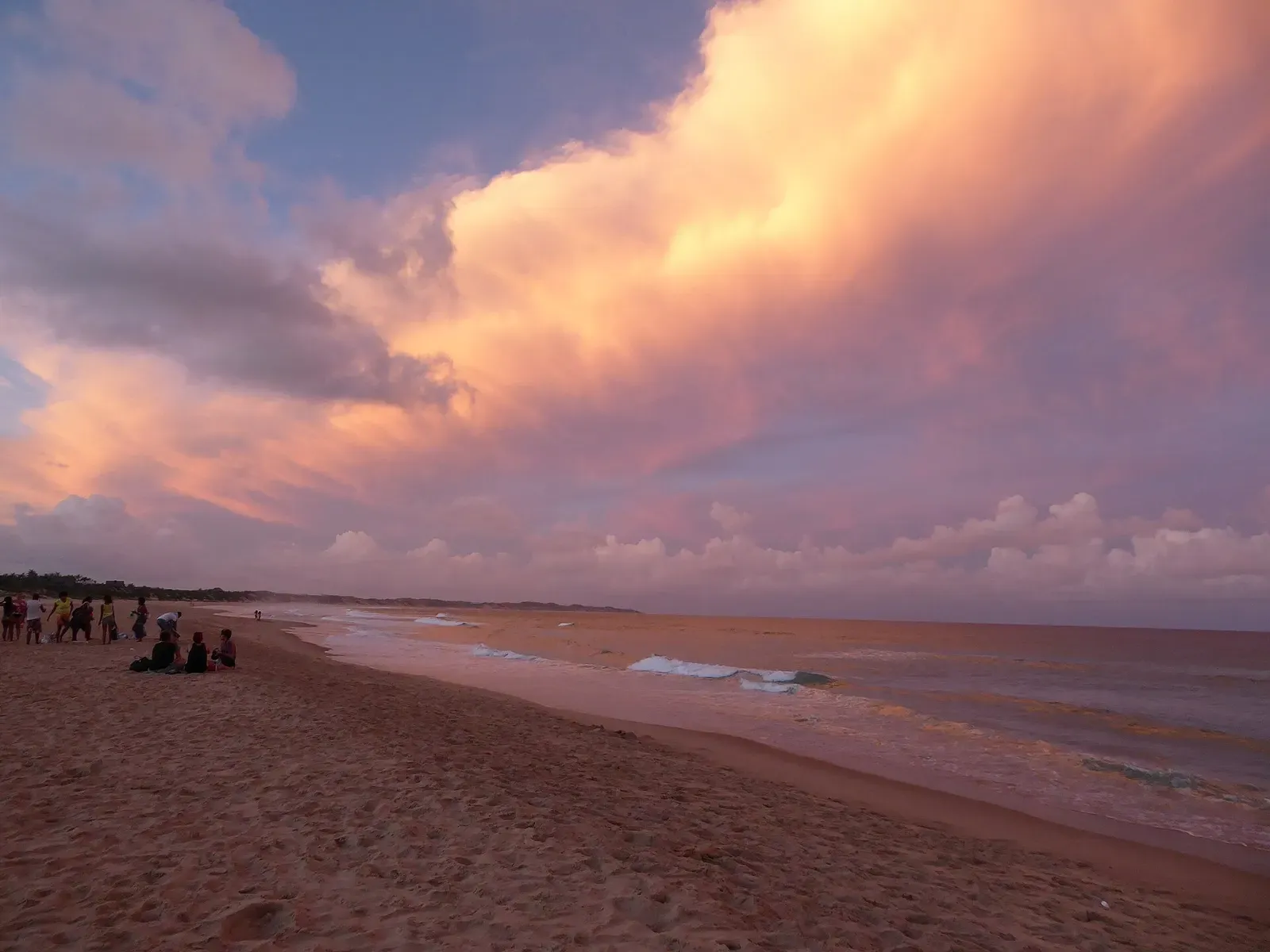 Sunset clouds glow pink and orange over the sandy shoreline at Tofo Beach.