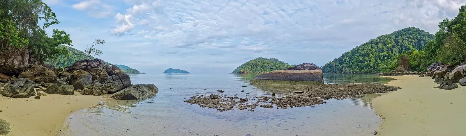 Panoramic view of a low-tide reef flat and sandy shore between two of the Surin Islands