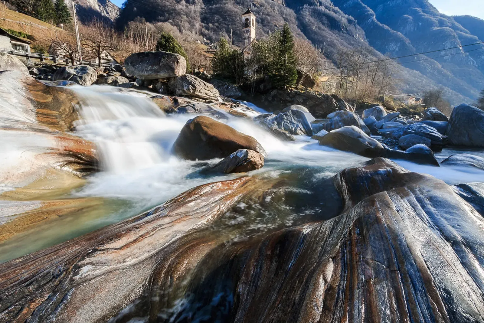Water cascading over smooth, striated granite slabs worn into curves by glacial meltwater